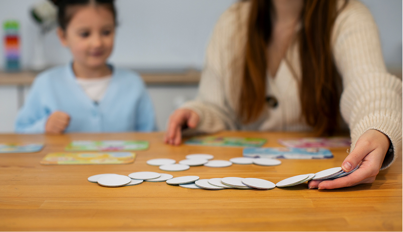 Niña en una sesión de intervención psicopedagógica con material didáctico sobre la mesa