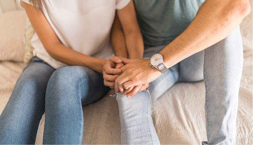 Pareja sentada en un sofá tomados de la mano durante una sesión de terapia